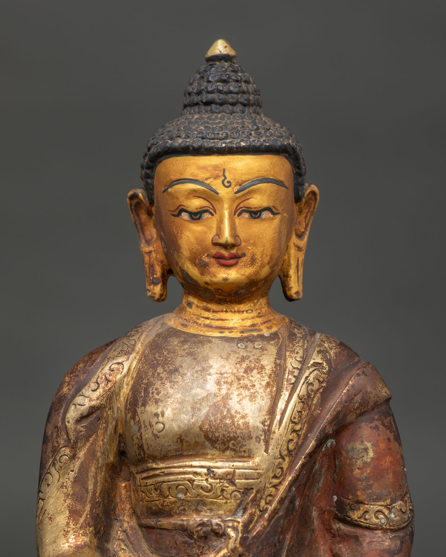 Detailed Amitabha Buddha face and monk robe with intricate Newari craftsmanship gold fire-gilded copper.