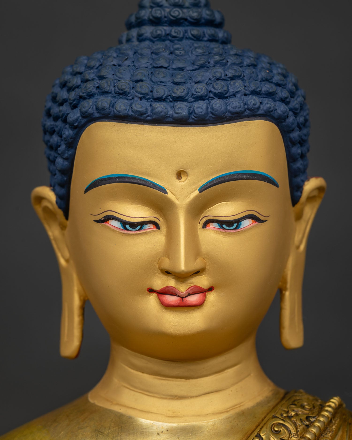 Detailed close up of 24K gold painted serene face on Shakyamuni Buddha statue from Nepal