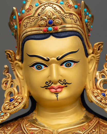 Detailed close-up of Guru Rinpoche face with gold-painted features and delicate carving