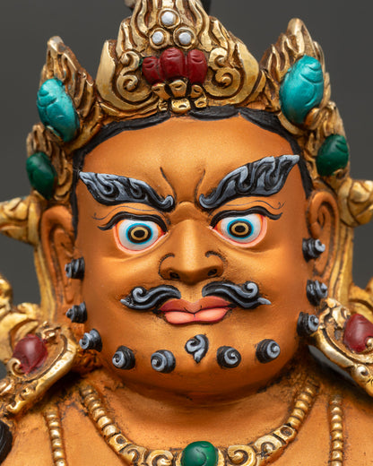 detailed close up face of yellow dzambhala wealth deity statue showing serene expression crown halo and intricate gold work