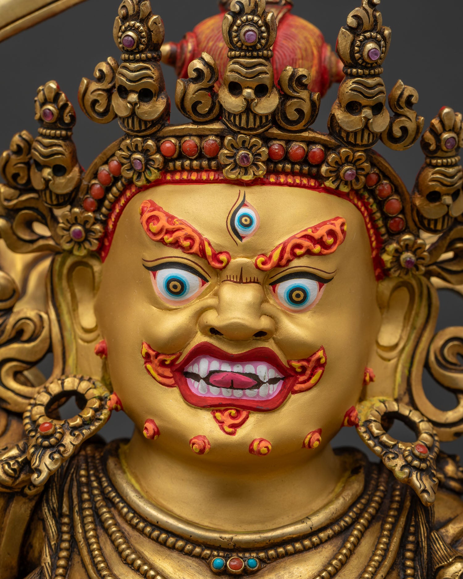 Detailed close-up of Black Manjushri's hand-painted gold face with fierce gaze and bared fangs
