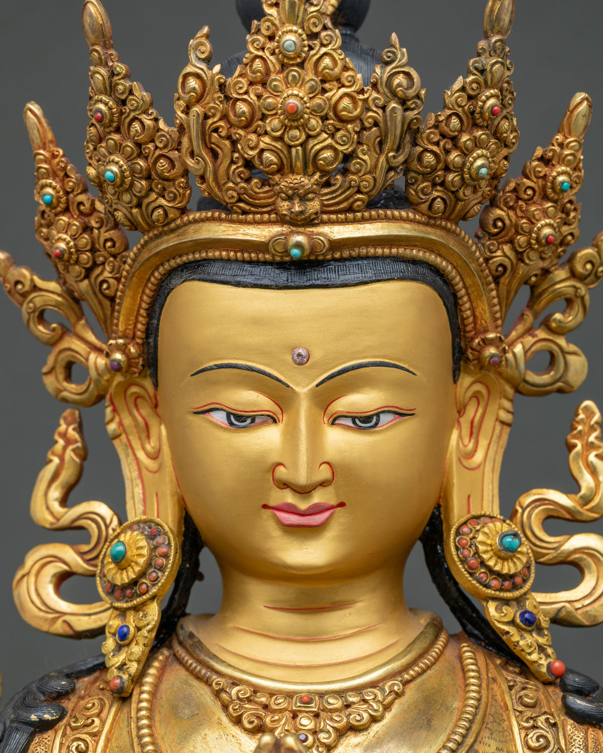 Detailed close-up of Chenrezig statue face with gold-painted features and jeweled five-point crown