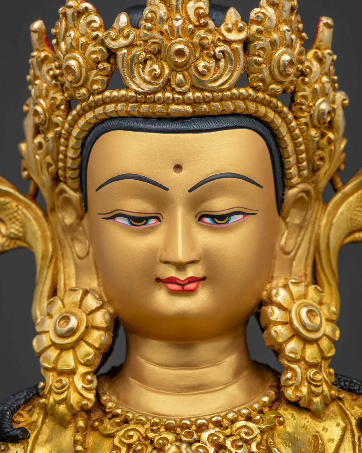 Detailed close-up of Chenrezig statue's gold-painted face and serene expression