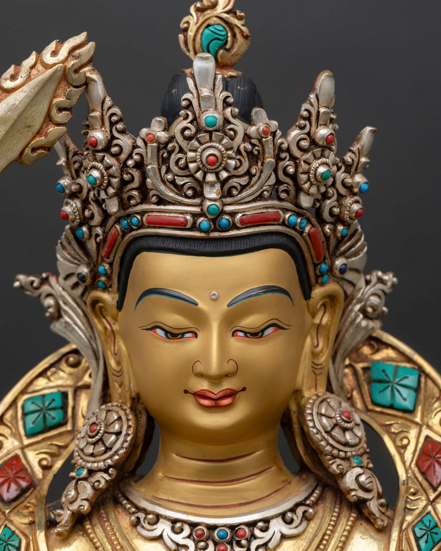 Detailed close-up of Manjushri face, serene expression, gold painted face, silver plated ornaments
