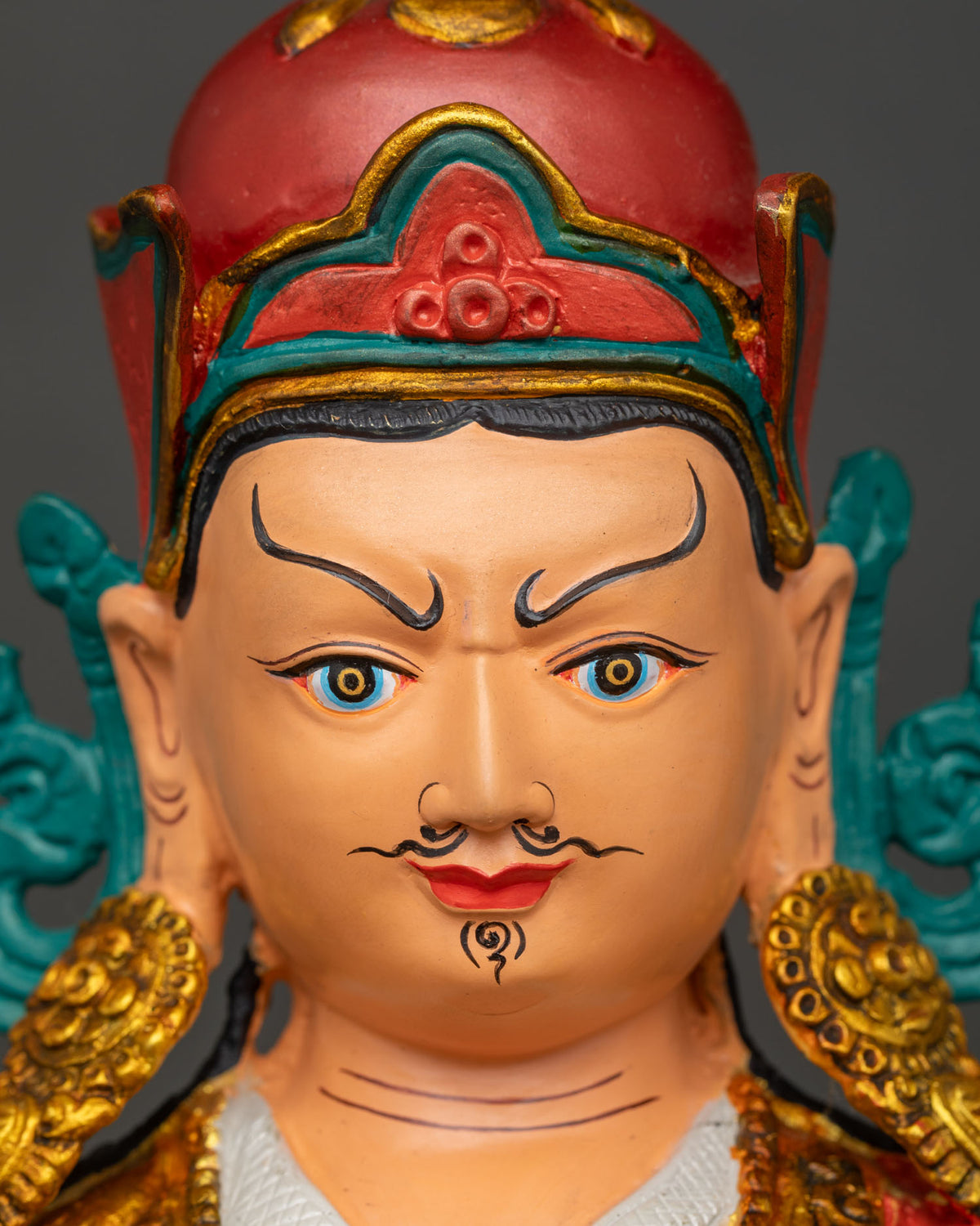 Detailed close up of Padmasambhava statue face, hand-painted Guru Rinpoche with gilded lotus hat