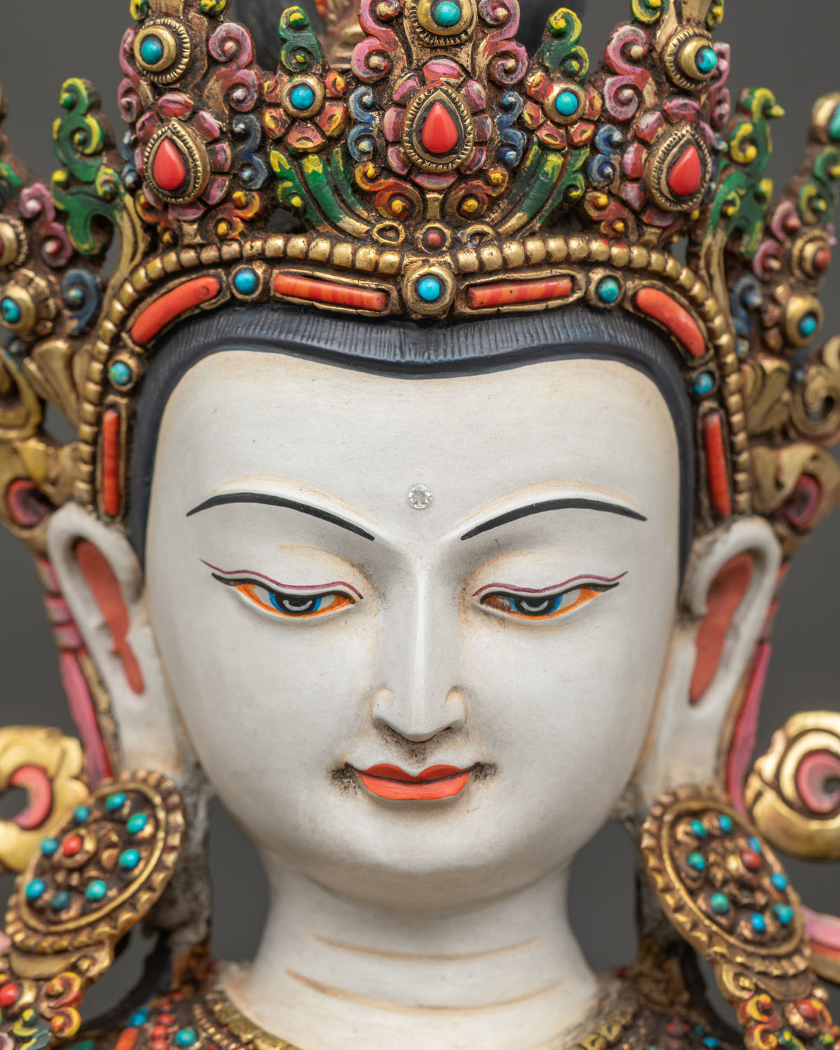 Detailed close up of serene gold painted face on Chenrezig statue