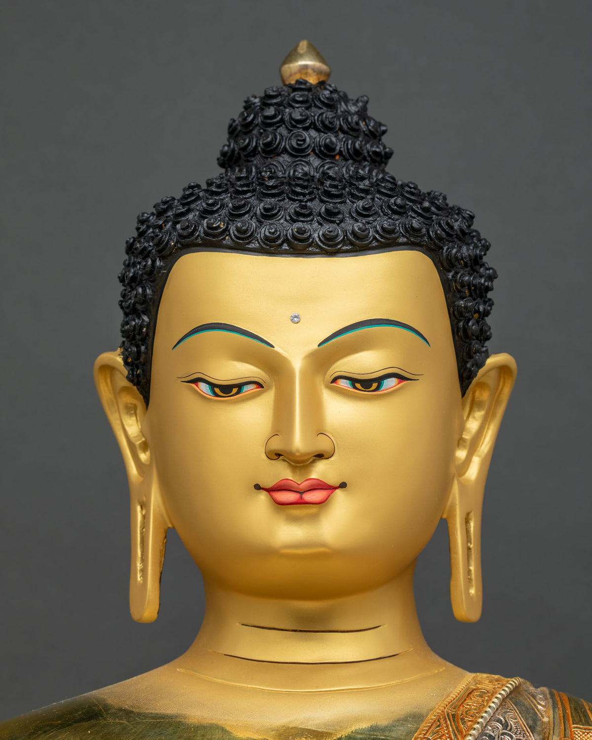 Detailed close up of Shakyamuni Buddha statue face with gold-painted features and half-closed eyes