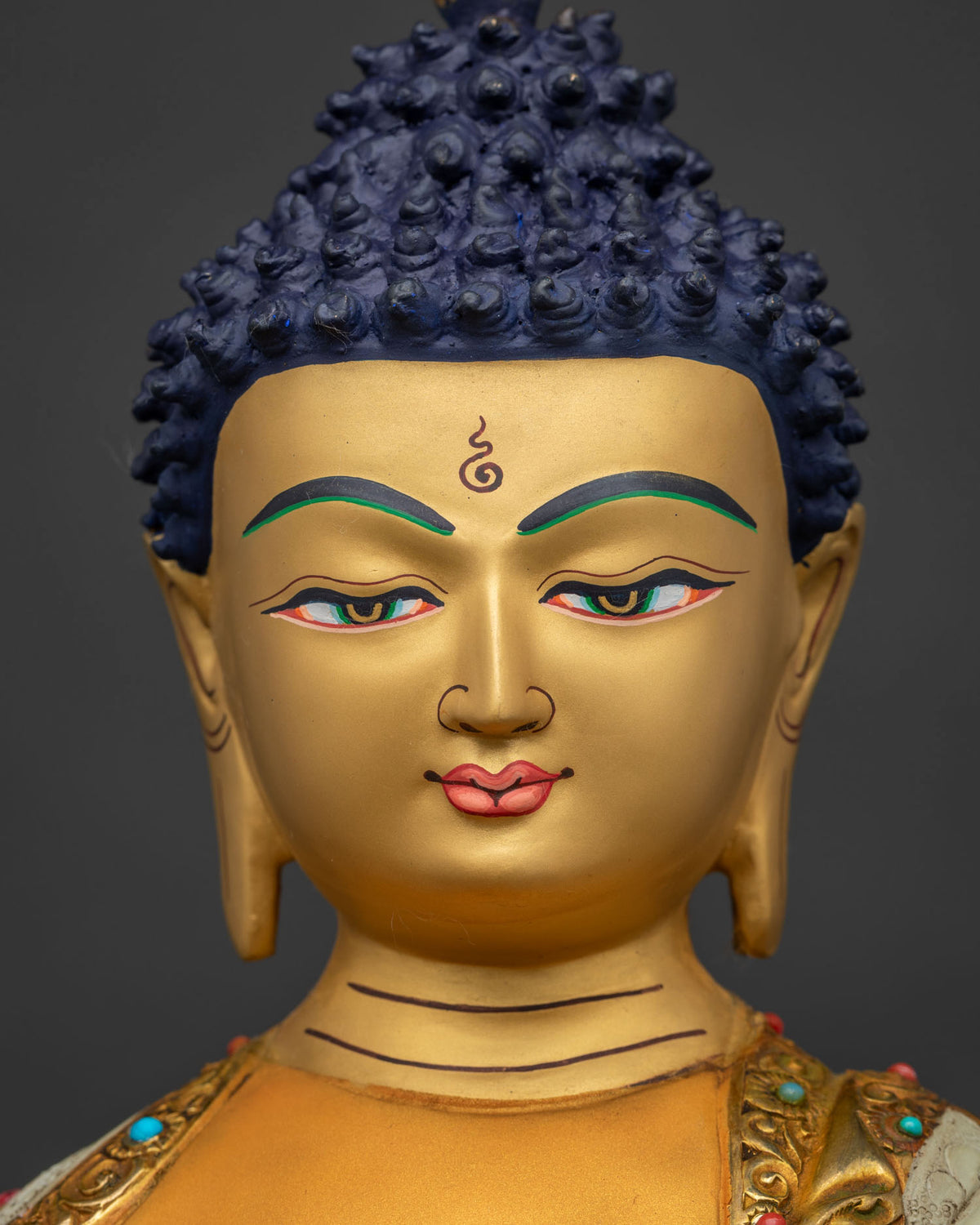 Detailed close-up of Shakyamuni Buddha's gold-painted face with tranquil downcast eyes