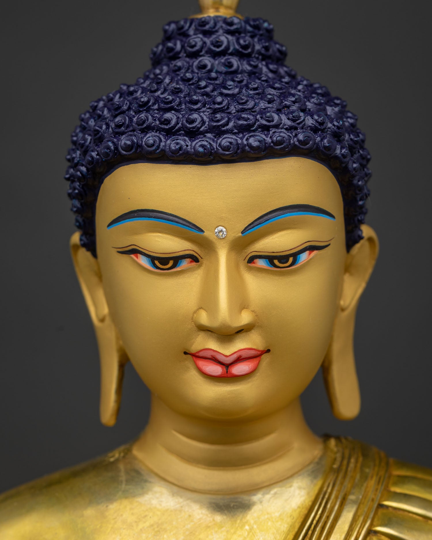Detailed close-up of Shakyamuni Buddha's serene face with hand-chased gold finish