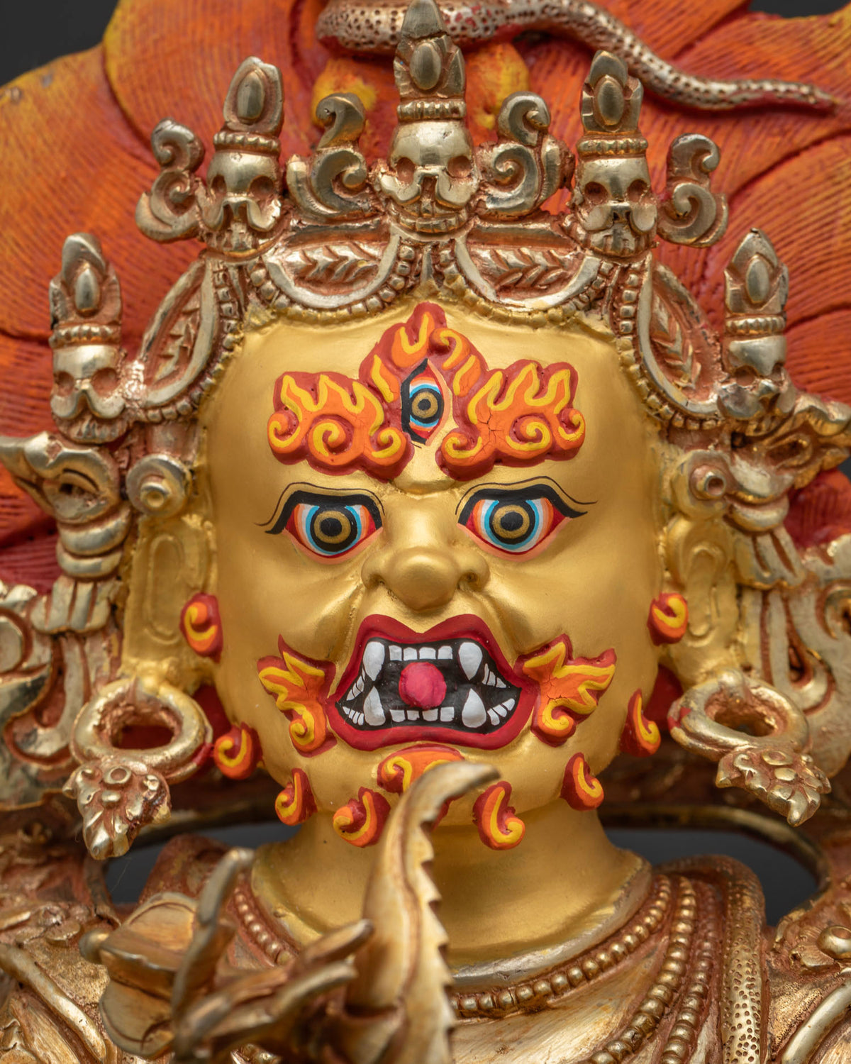 Detailed close up of Six Arm Mahakala face with third eye, bared fangs and gold painted finish
