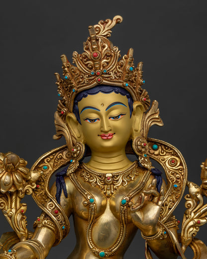 Detailed close up showing Green Tara Buddhist sculpture with gold-painted face and gemstone ornaments