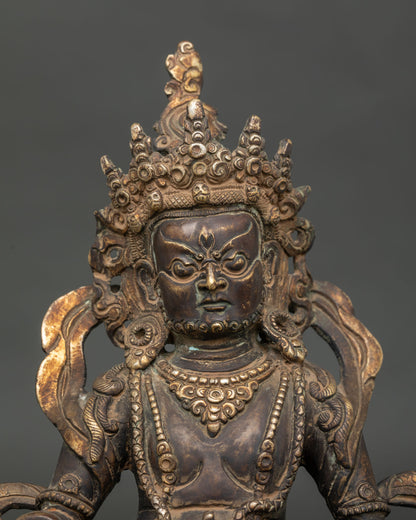 Detailed Dzambhala statue face with five jewel crown flowing scarf and royal garments.