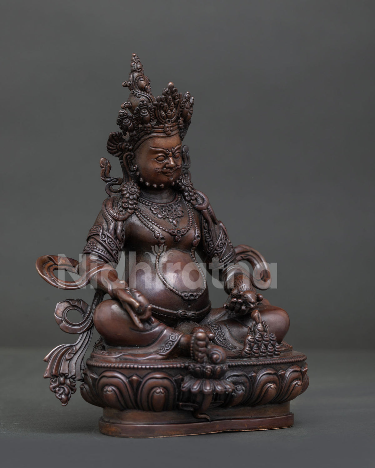 Detailed Dzambhala statue with ornate earrings layered necklaces and lotus pedestal.