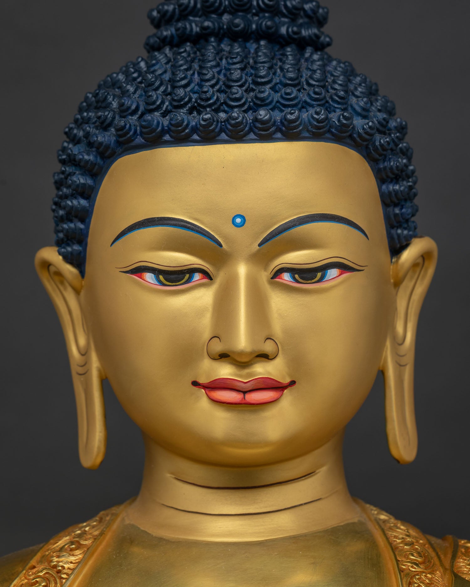 Detailed face close-up of gold gilded Buddha statue displaying hand-painted facial features