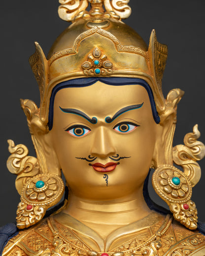 Detailed face close up of gold Padmasambhava statue featuring tranquil expression and lotus hat.