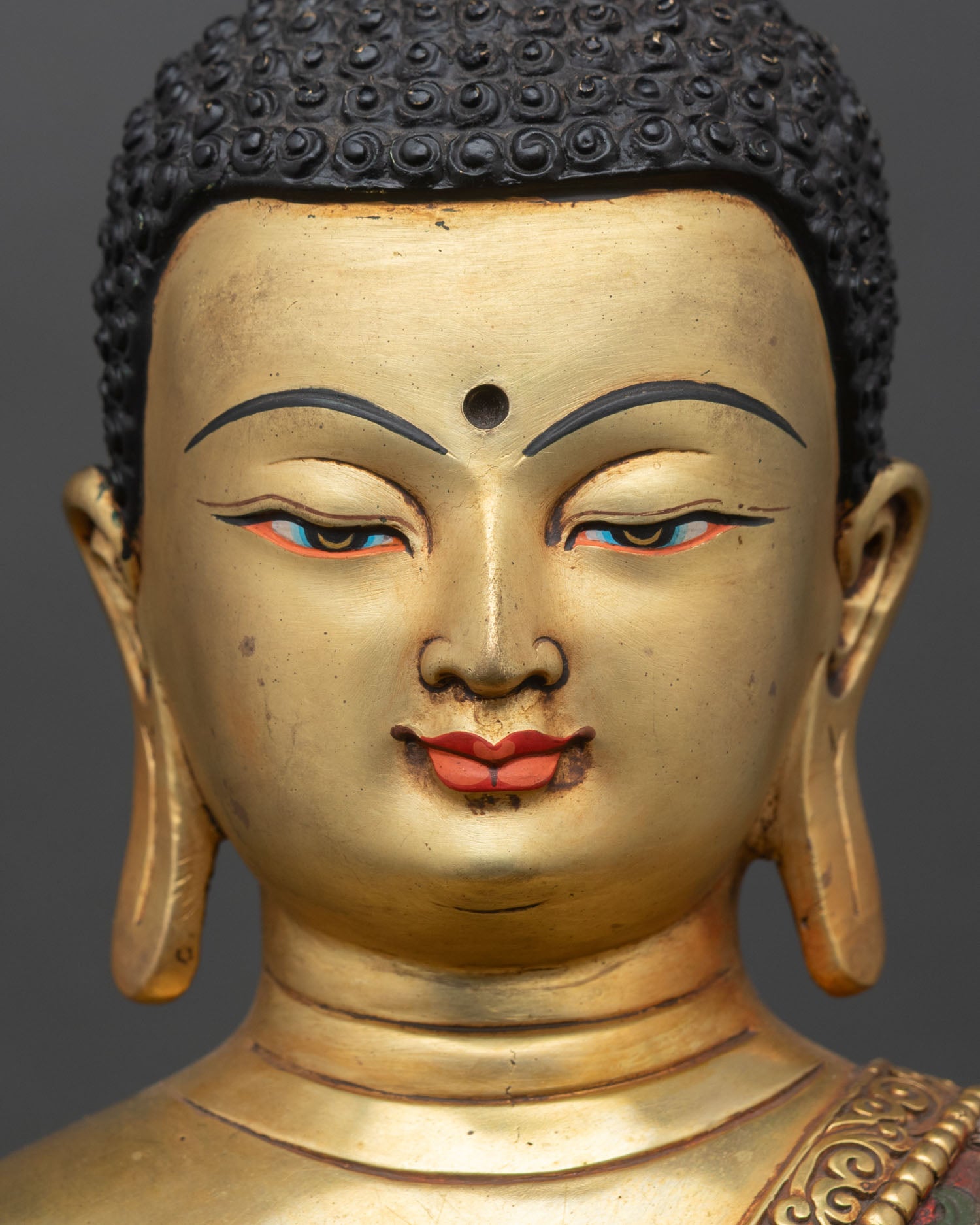 detailed face close up of shakyamuni buddha statue with gold gilding and calm expression