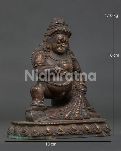 Detailed face of Black Dzambhala Statue with fierce expression and antique copper craftsmanship.