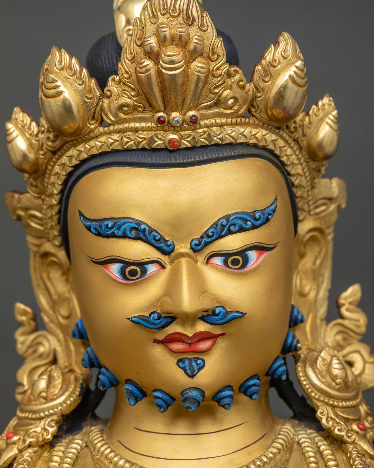 Detailed face of Dzambhala copper statue with hand-painted eyes, mustache and beard