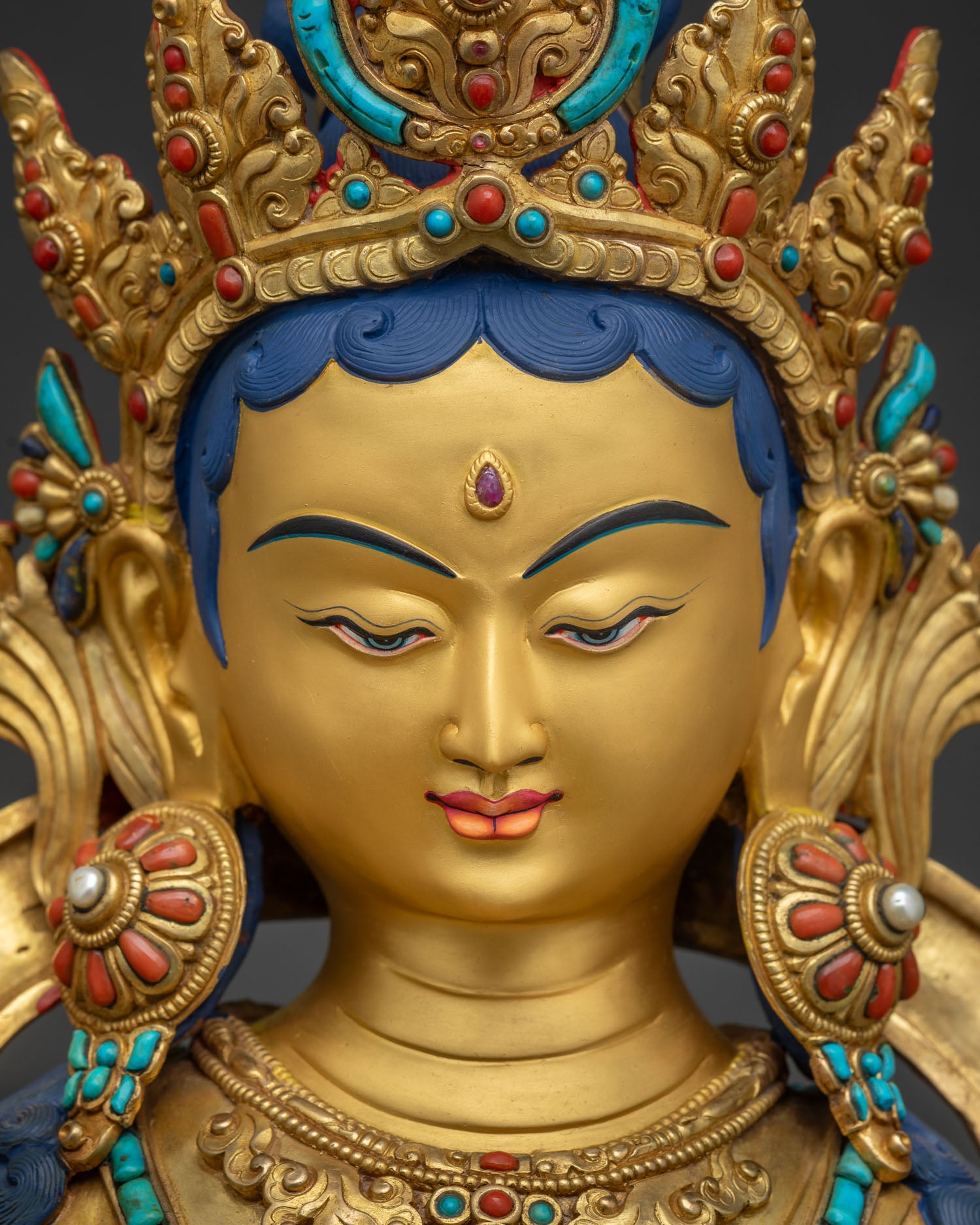 Detailed face of Green Tara statue featuring 24K gold paint, serene gaze, and jeweled crown.