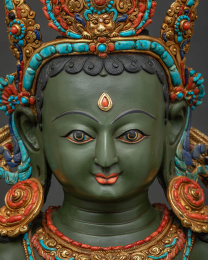 Detailed face of Green Tara statue showing serene expression hand painted details and gemstone crown.