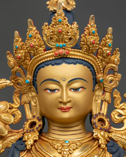 Detailed face of Green Tara statue with serene gold-painted expression and jeweled crown