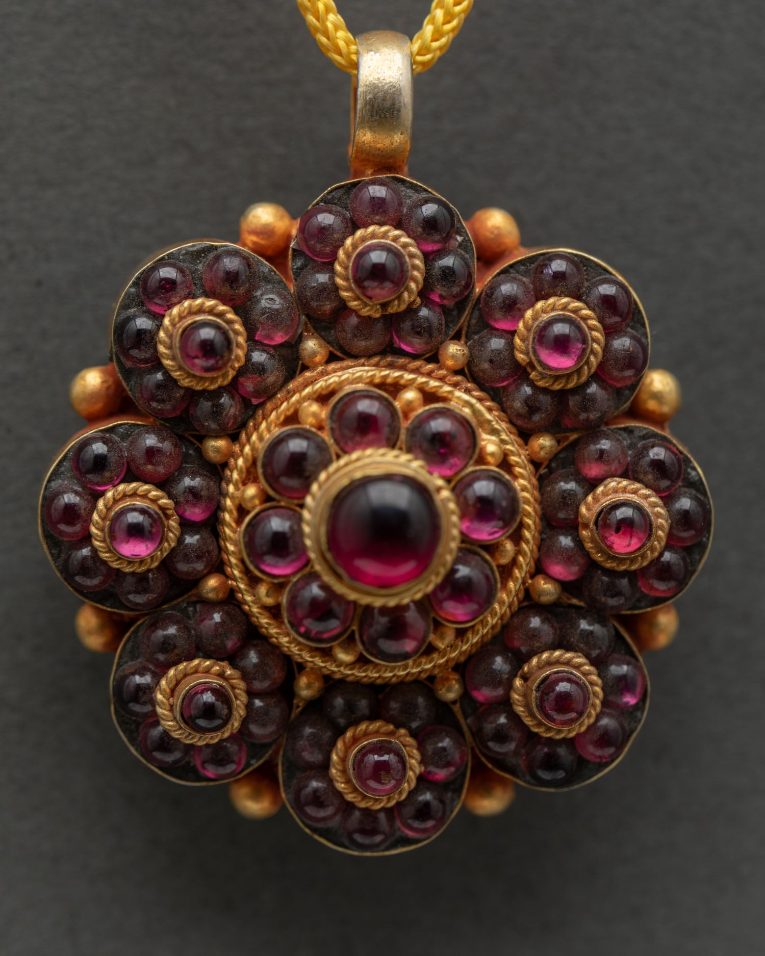 Detailed floral design of handcrafted copper locket with rhodolite garnet stones