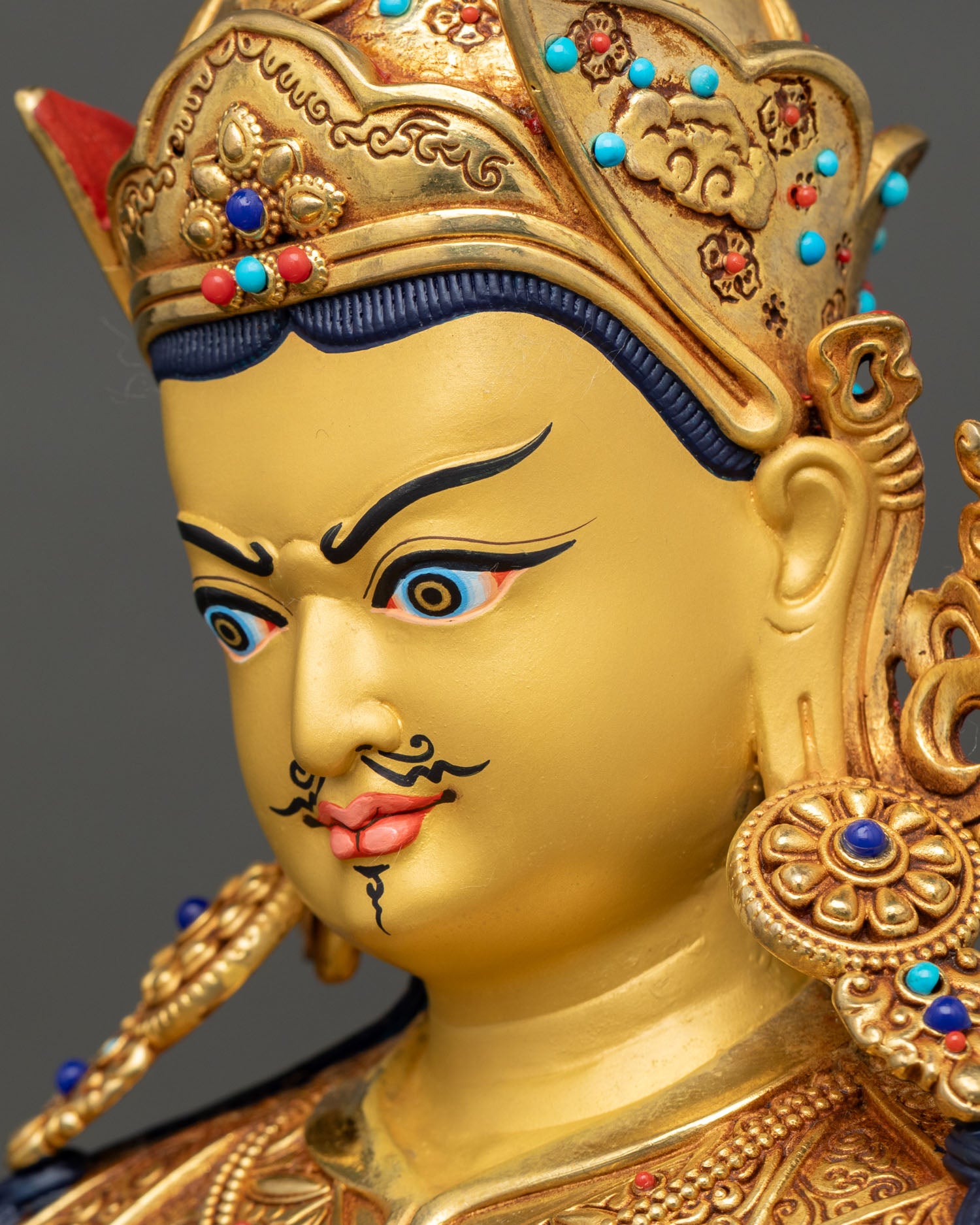 Detailed side close-up of Guru Rinpoche face showing copper and gold craftsmanship