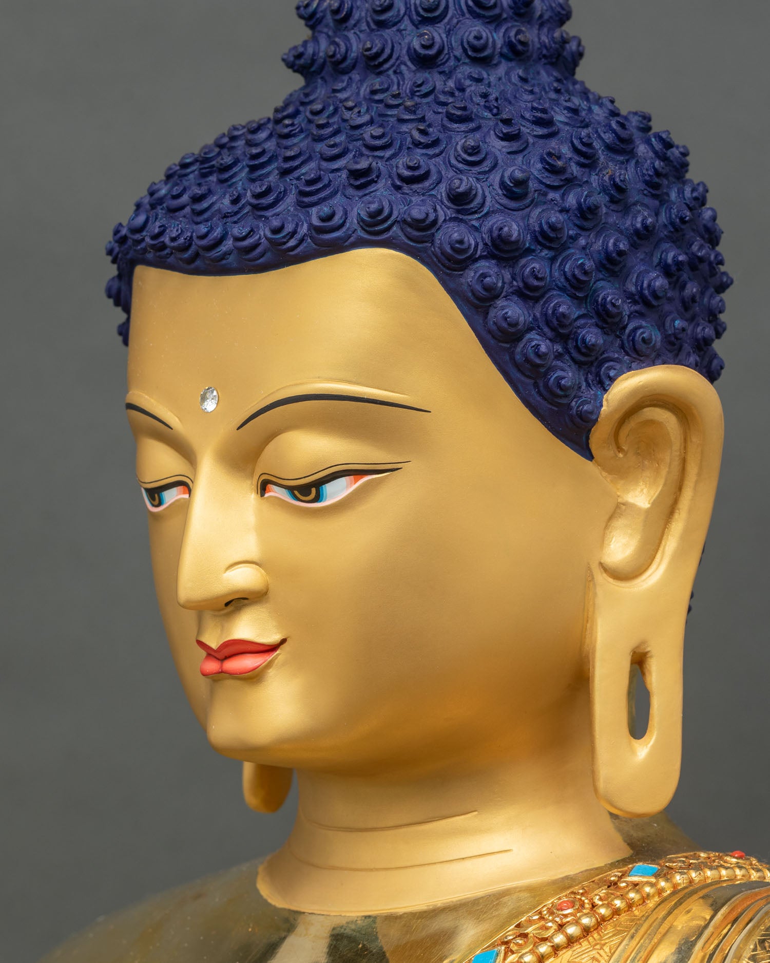 Detailed side close-up of Buddha face showing painted features and semi-precious stones