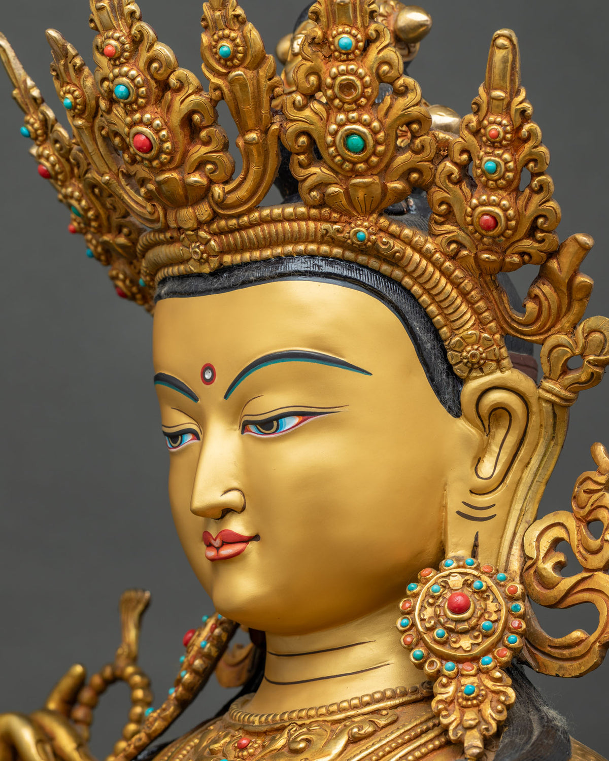 Detailed side close-up of Chenrezig statue face, gemstone earring and hand-chased crown