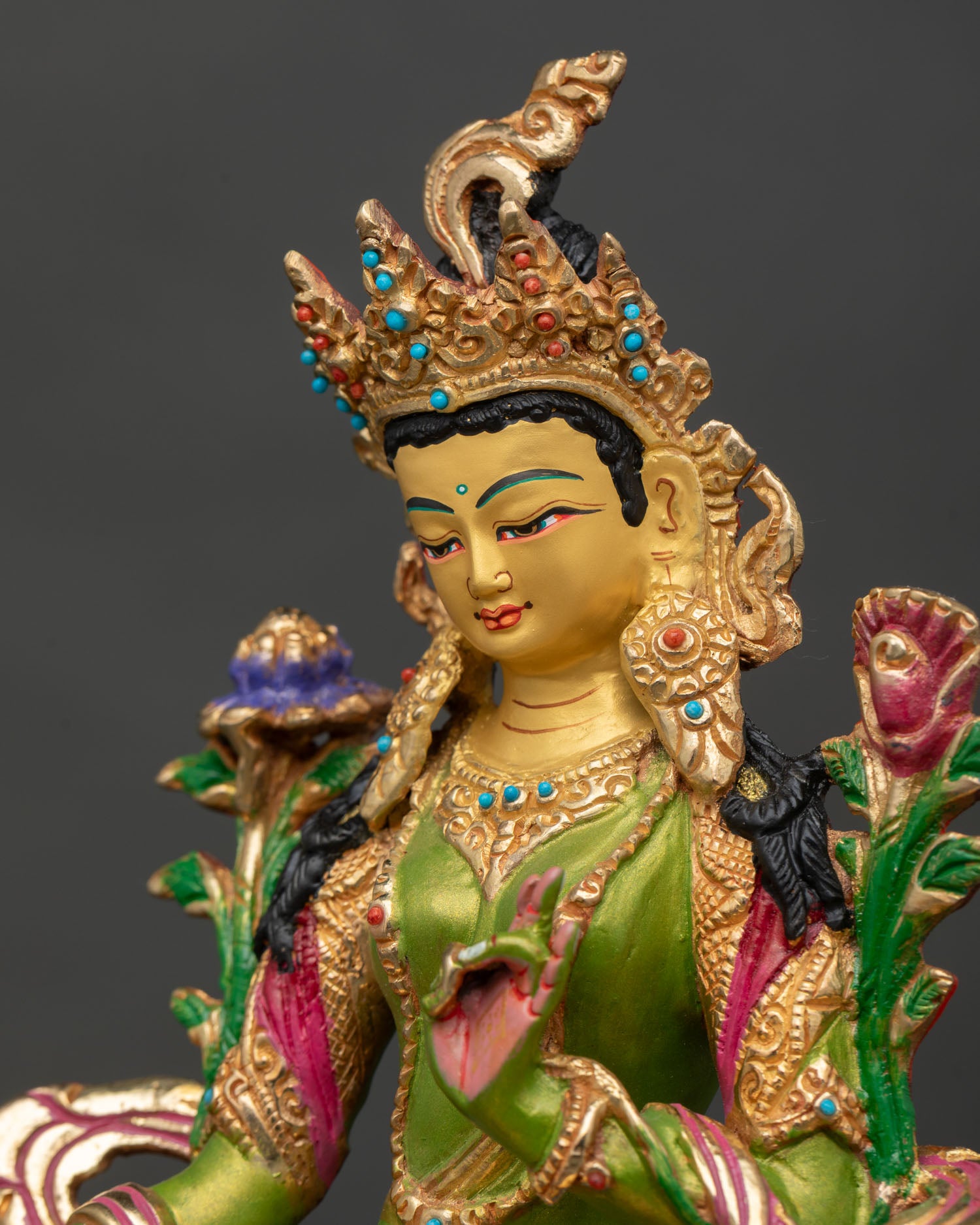 detailed side close up of green tara figurine holding blue lotus on lotus throne