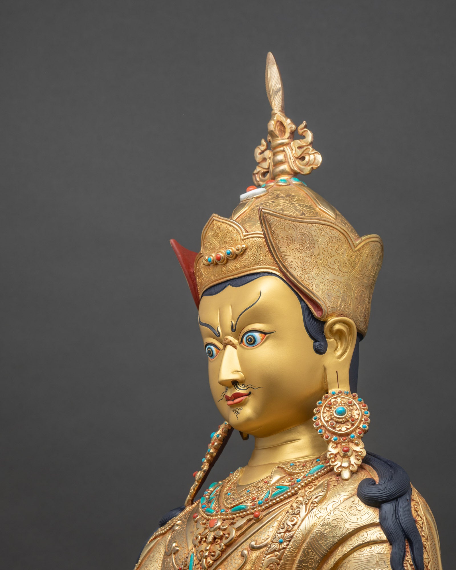 Detailed side close up of Guru Rinpoche statue showing robe carvings and gemstone ornaments