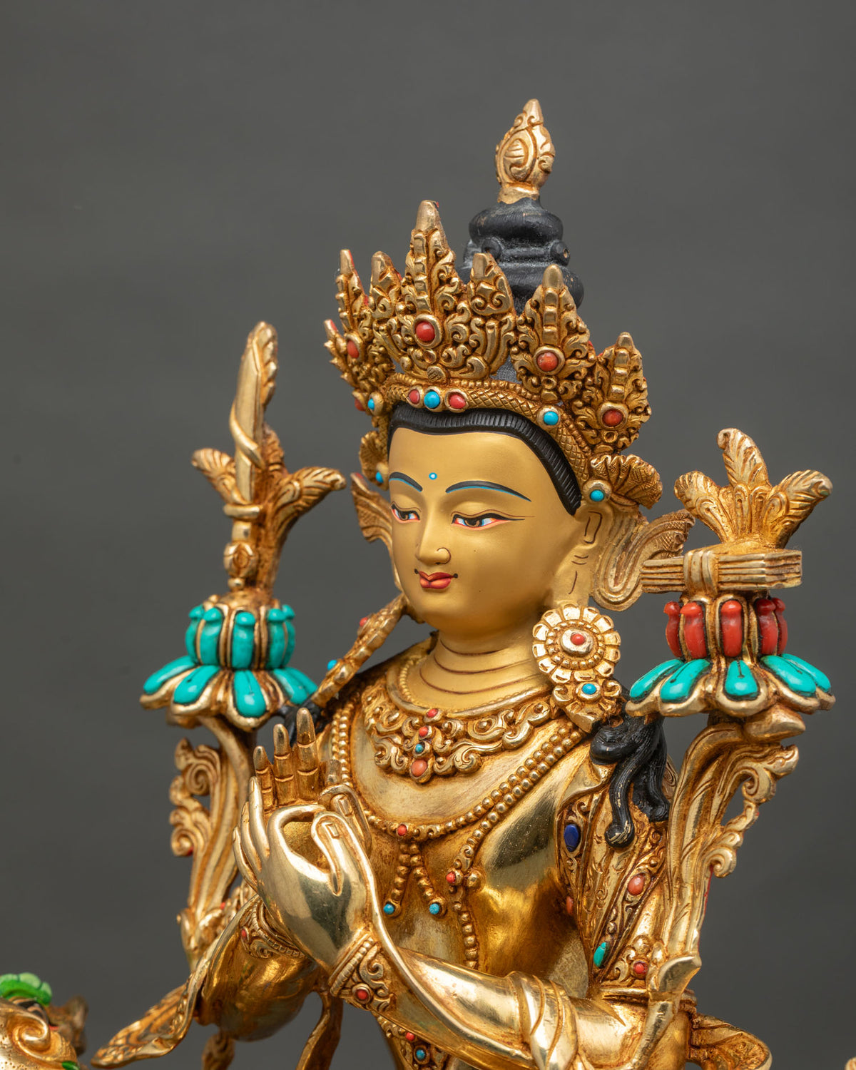 Detailed side close up of Manjushri statue with wisdom sword, scripture and turquoise coral inlays