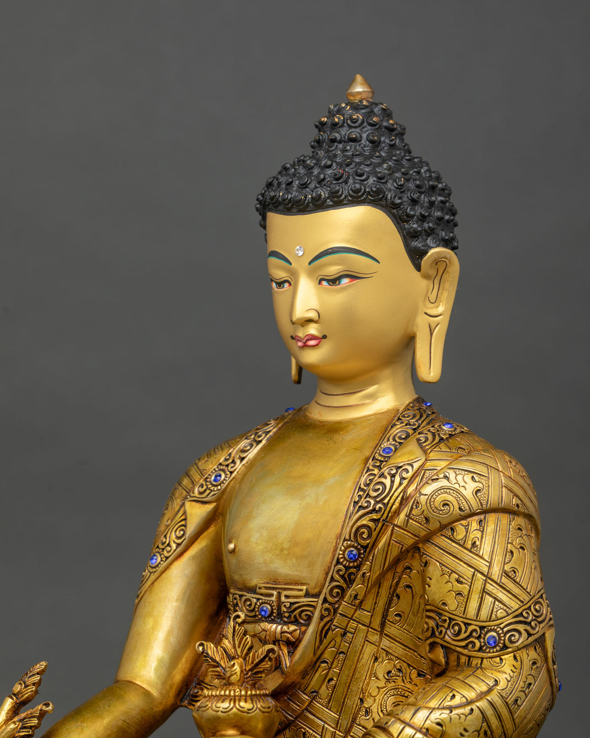 Detailed side close up of Medicine Buddha statue with hand-carved robe and myrobalan plant from Nepal