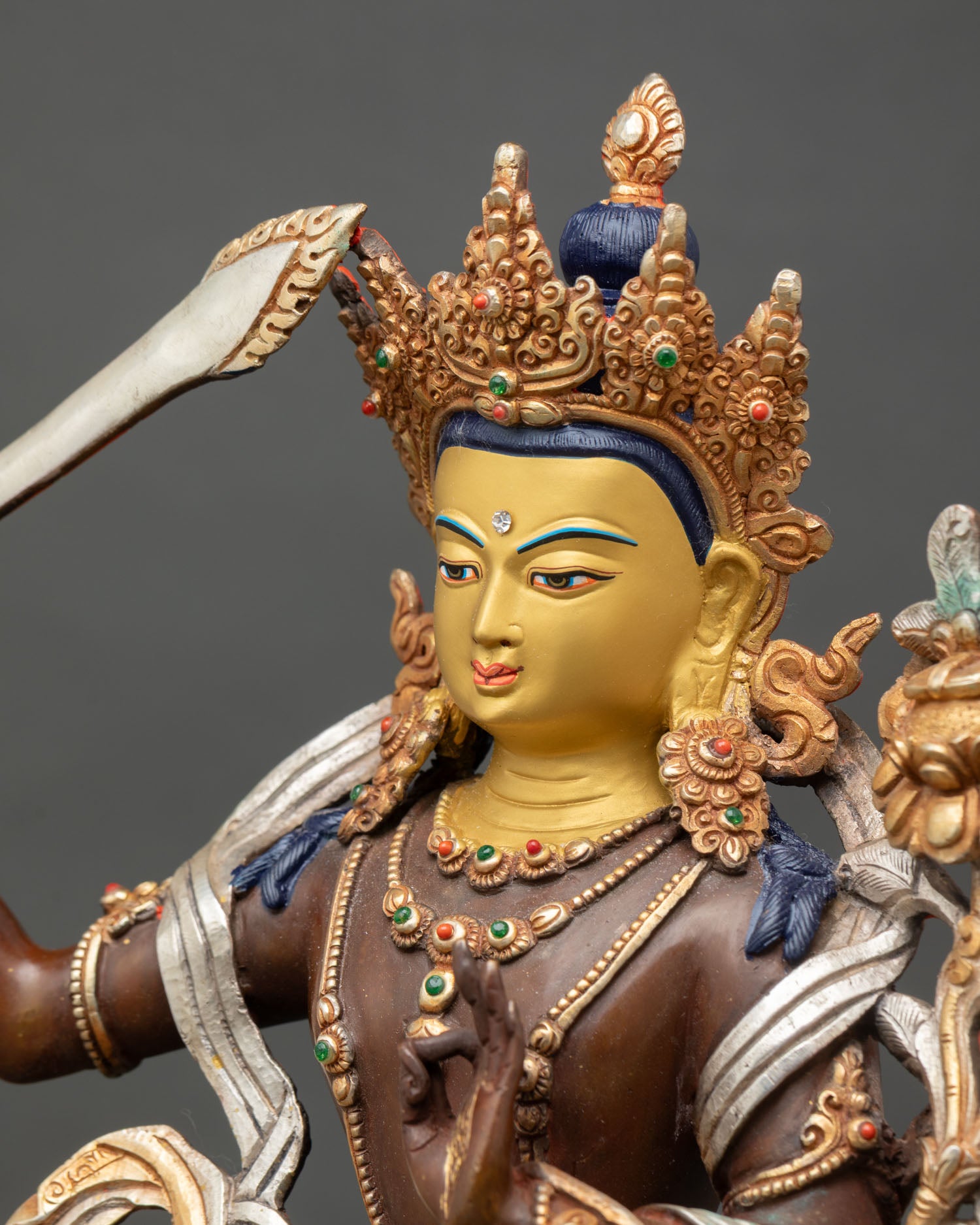 detailed side close up of oxidized manjushri statue with lotus and sword details