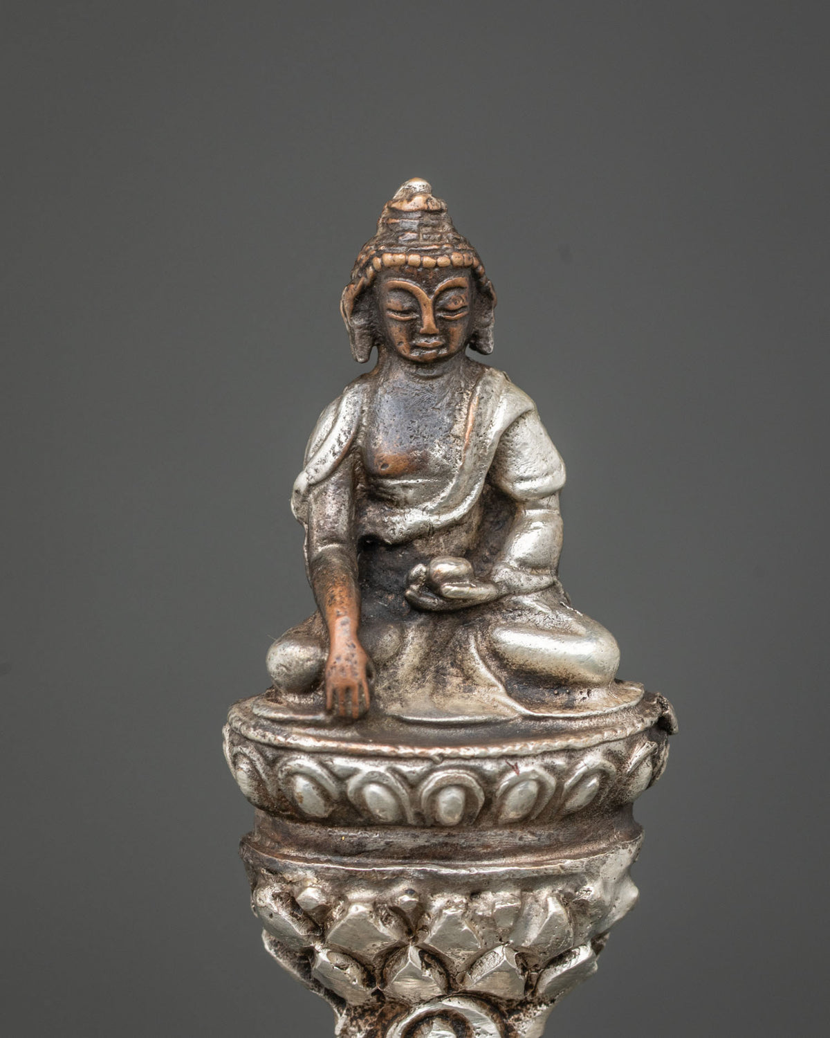 Detailed side close-up of Ucchusma statue showing silver-plated wheel, spear and ritual implements