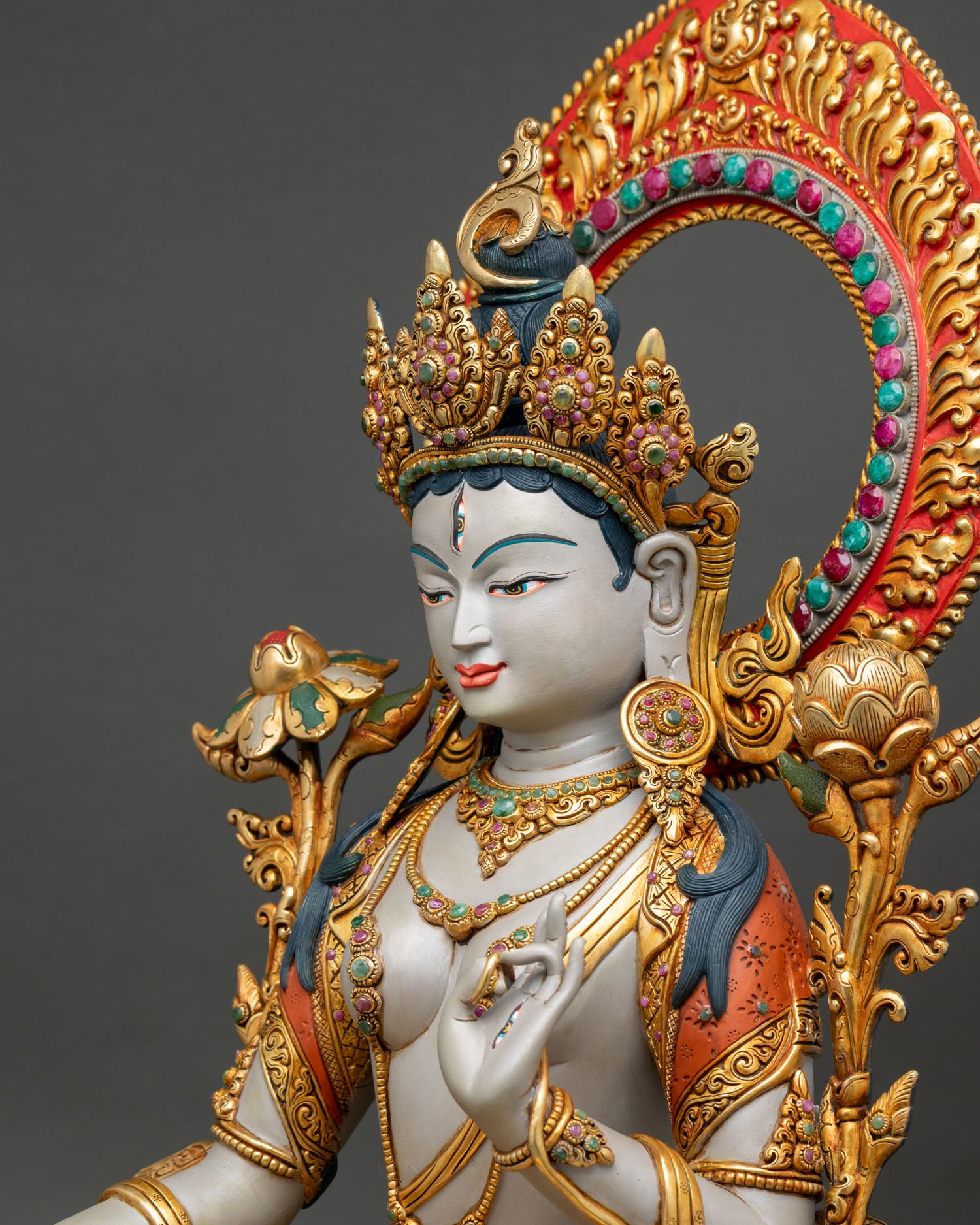 detailed side close up of white tara statue with lotus and jeweled decorations