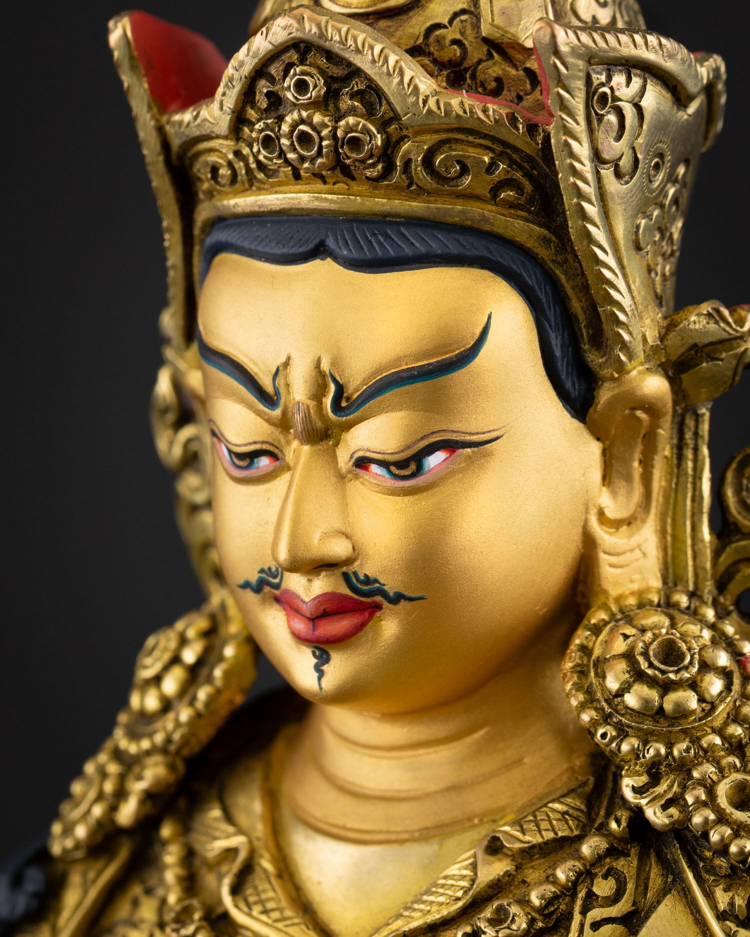 Detailed side face close up of Guru Tsokye Dorje with gold-painted serene visage