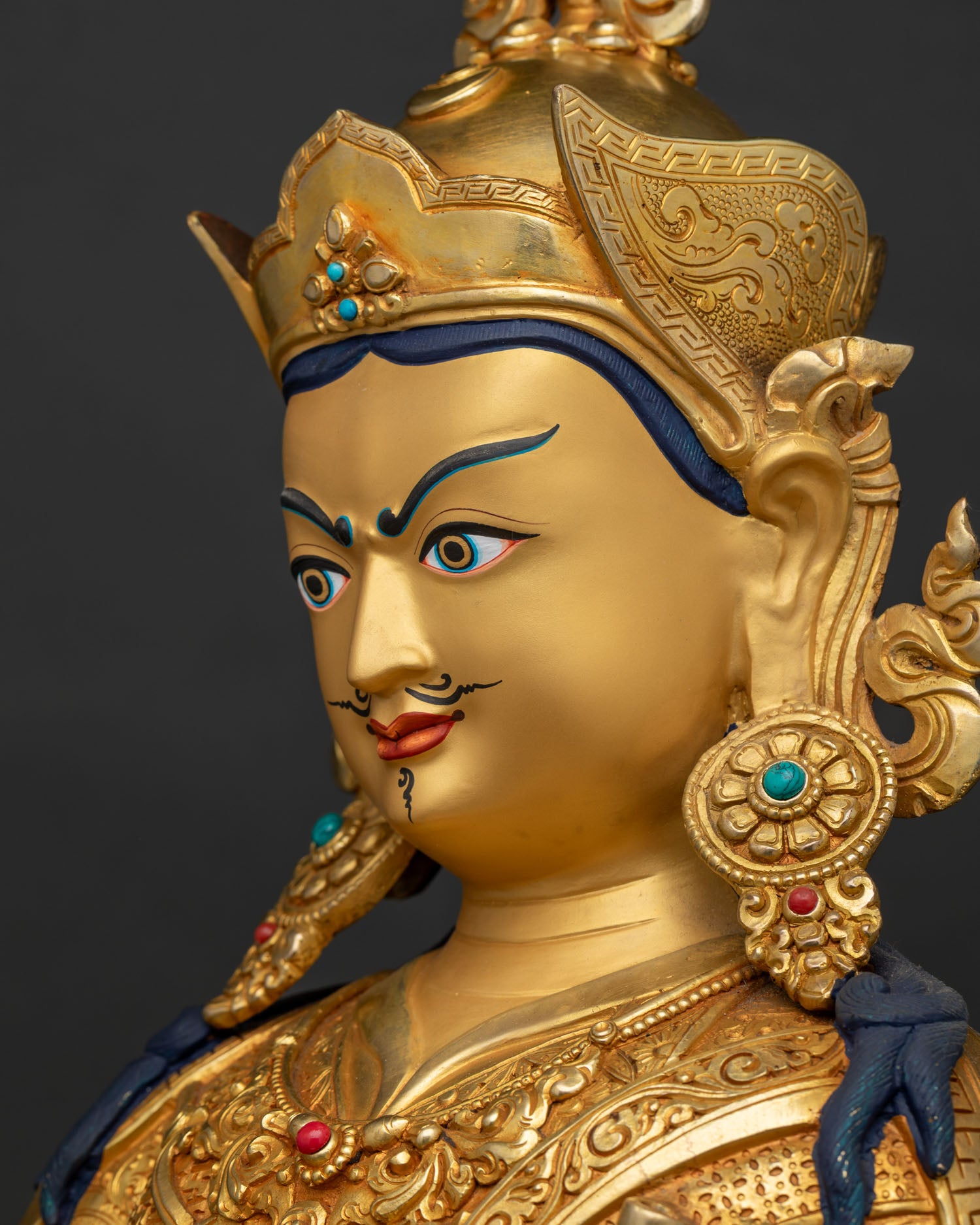 Detailed side profile of Padmasambhava statue face showing fine 24K gold gilding craftsmanship.