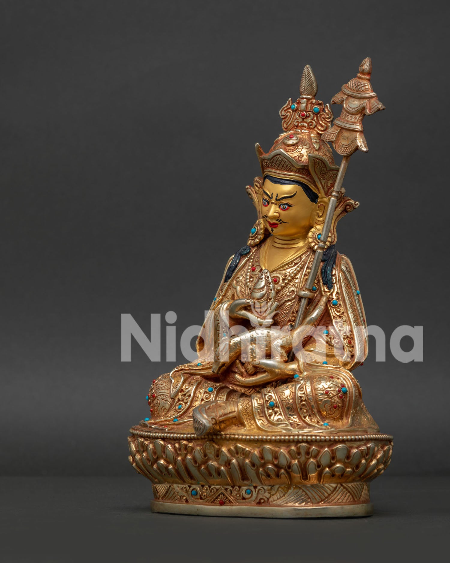 Detailed side view of Guru Rinpoche holding vajra kapala and khatvanga on lotus pedestal.