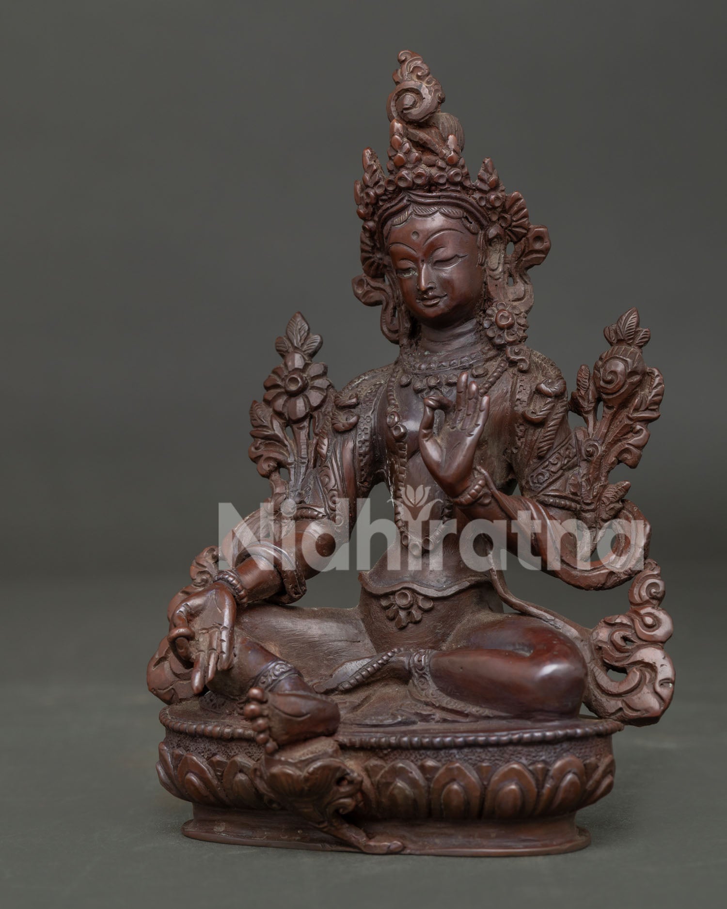 Detailed view of Green Tara seated with right leg extended holding sacred blue utpala lotus.