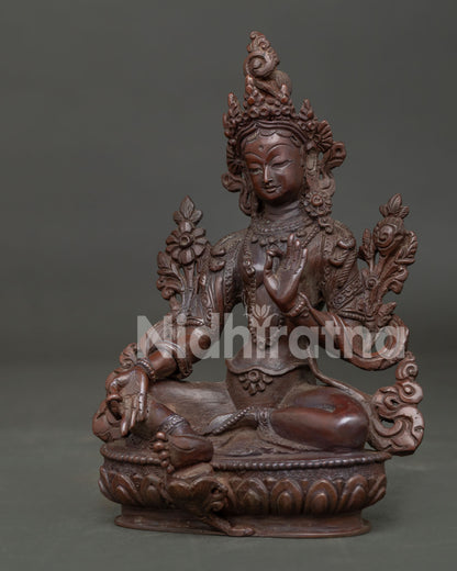 Detailed view of Green Tara seated with right leg extended holding sacred blue utpala lotus.