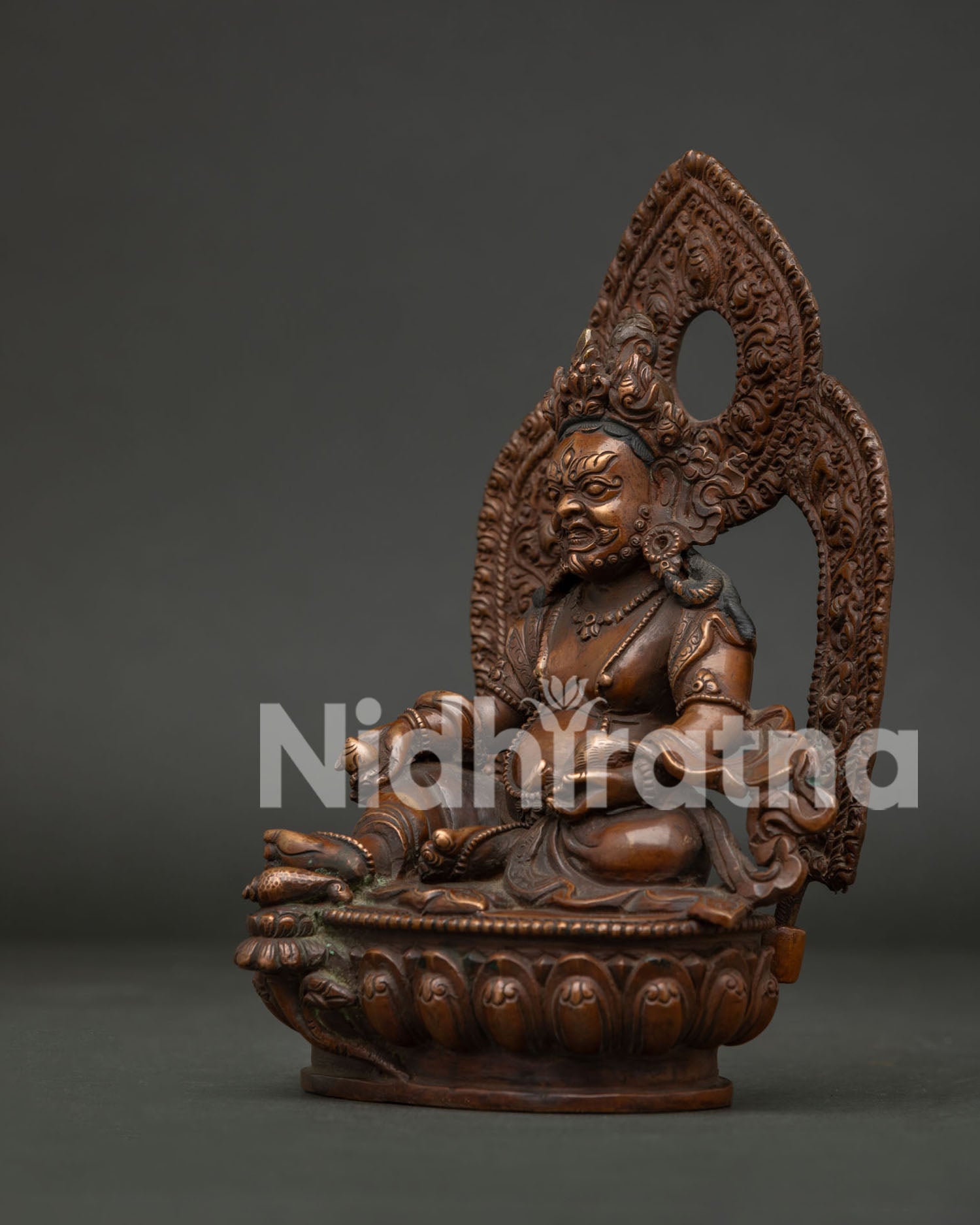 Detailed View of Oxidized Dzambhala Statue with Elaborate Halo Design.