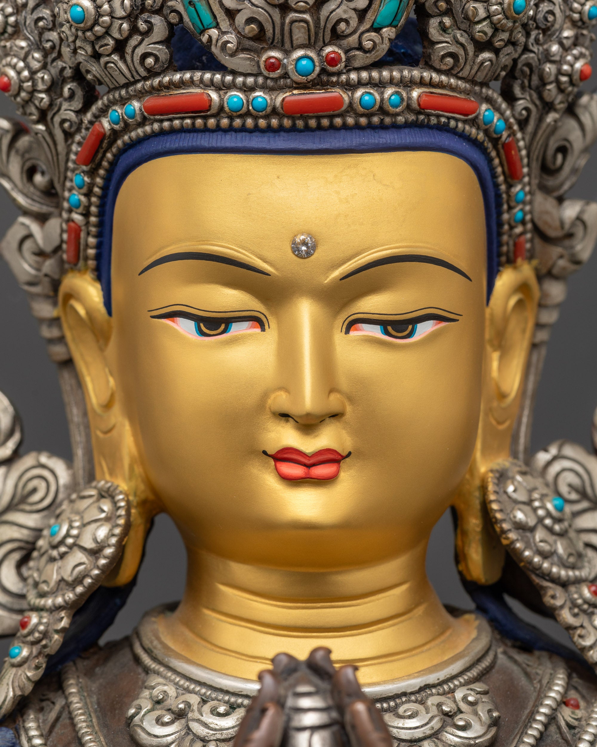 detailed close up face of oxidized Chenrezig statue with 24K gold-gilded calm expression