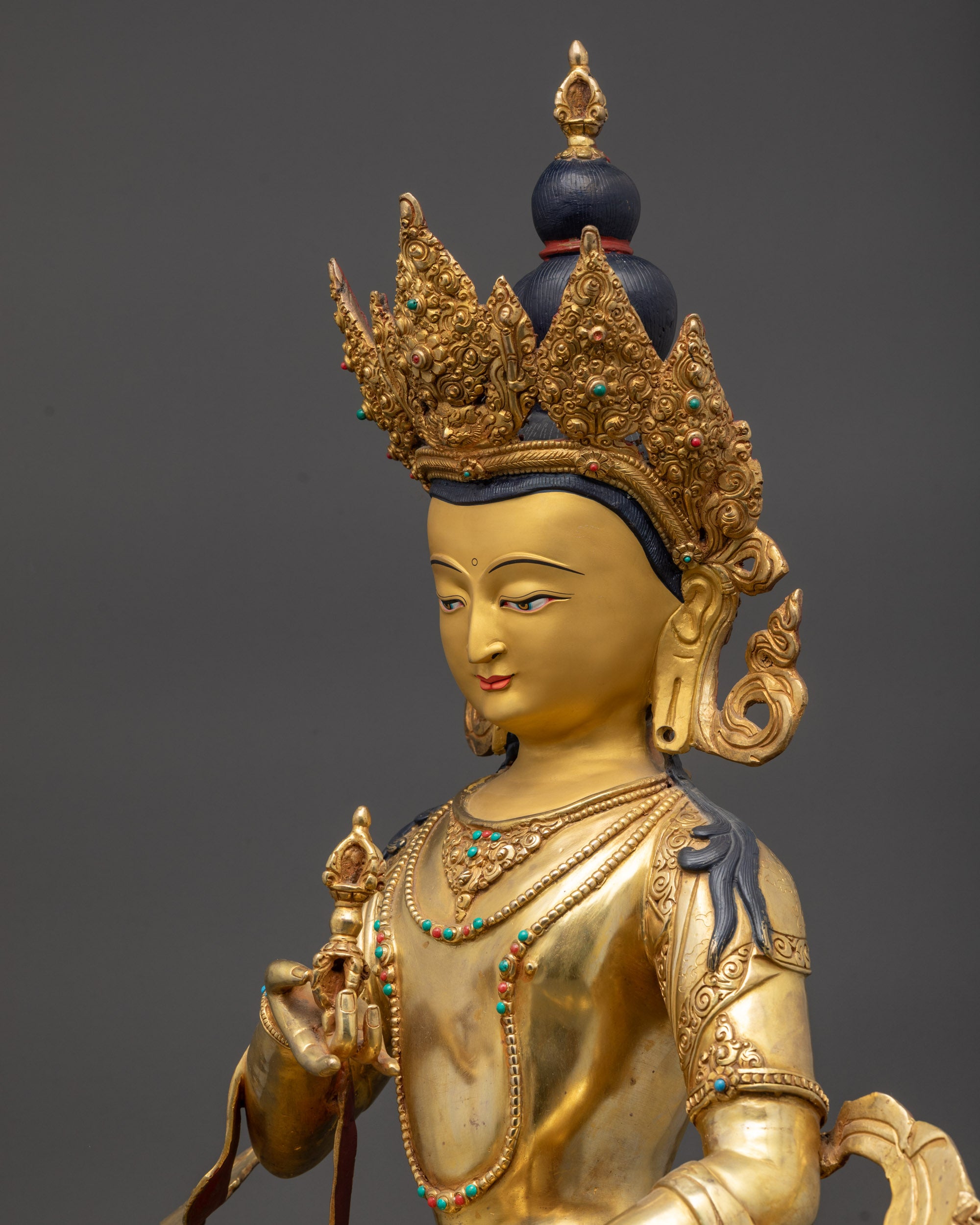 detailed side close up Vajrasattva statue showing dorje, ghanta, and robe carvings
