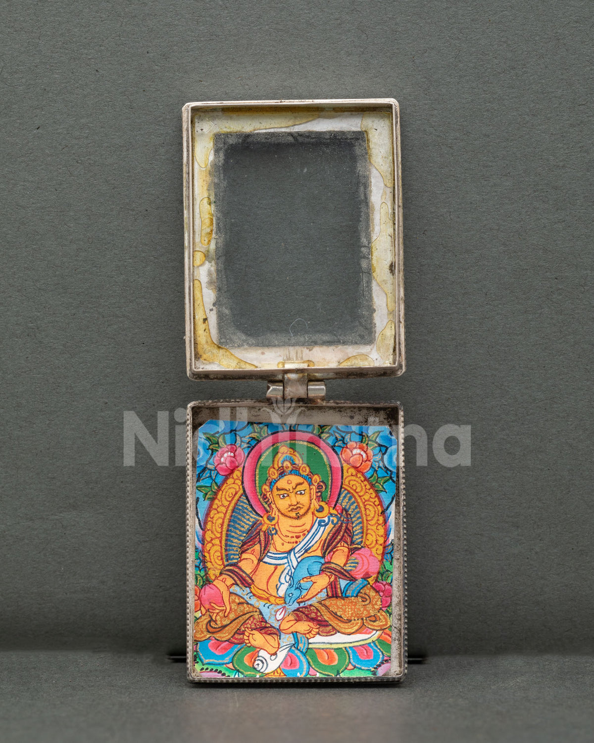 Dzambhala locket handcrafted from pure silver with intricate filigree patterns and semi-precious coral stones by a Newari artist in Patan, Nepal.