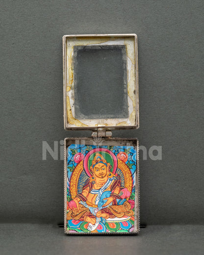 Dzambhala locket handcrafted from pure silver with intricate filigree patterns and semi-precious coral stones by a Newari artist in Patan, Nepal.