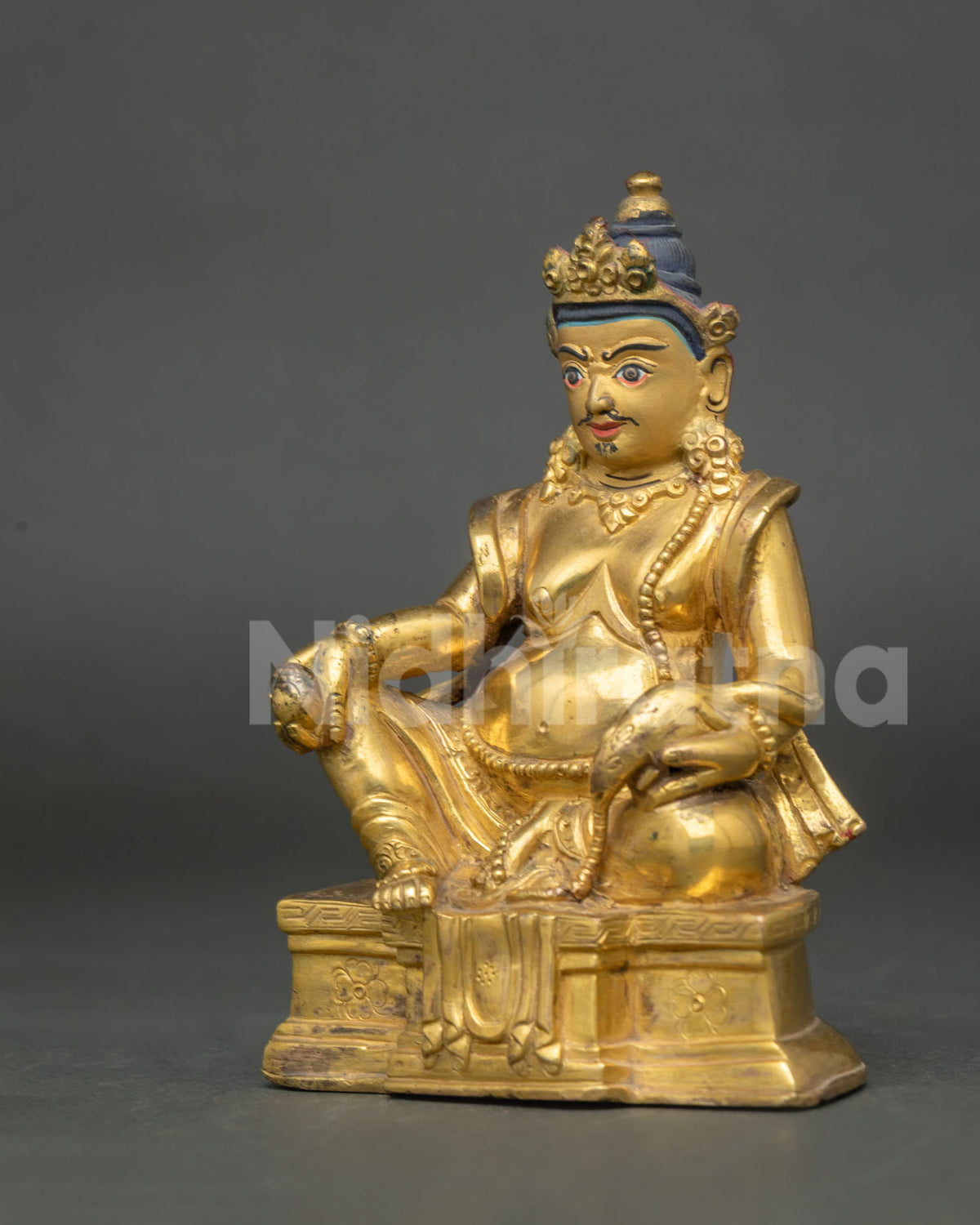 Dzambhala statue elaborate crown jewelry and ornate throne detail view.