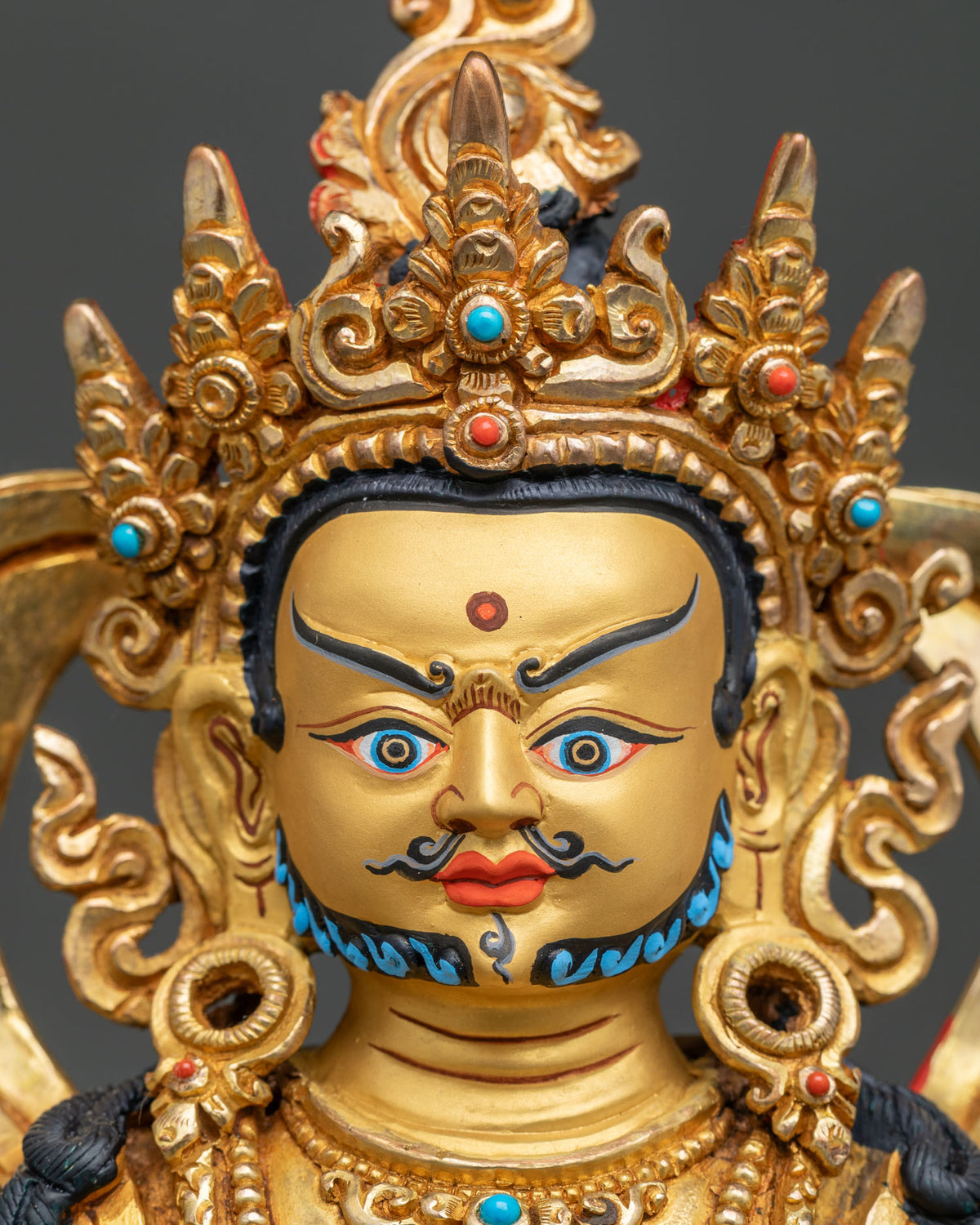 Dzambhala statue face close up 24K gold painted face conch shell crown.