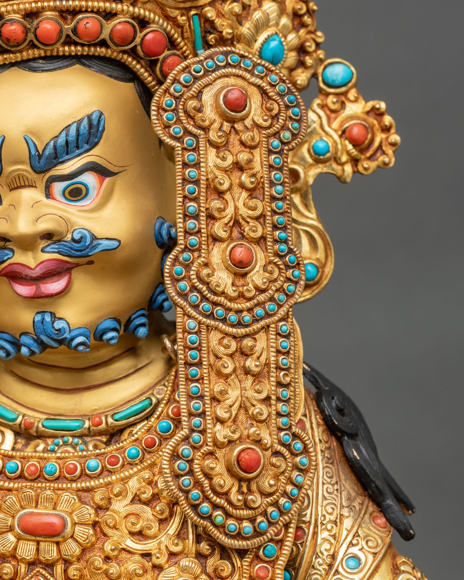 Dzambhala statue left earring close-up turquoise coral gemstone gold filigree detail