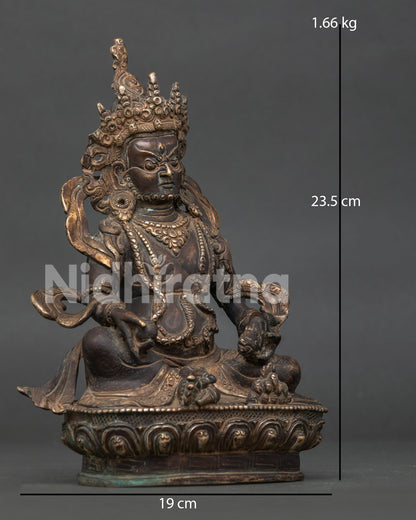 Dzambhala statue seated on lotus pedestal holding treasure spouting mongoose and citron fruit.